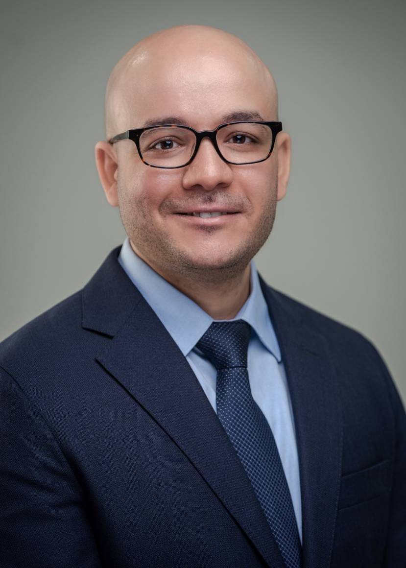 Professional headshot of a male dentist wearing glasses and business attire